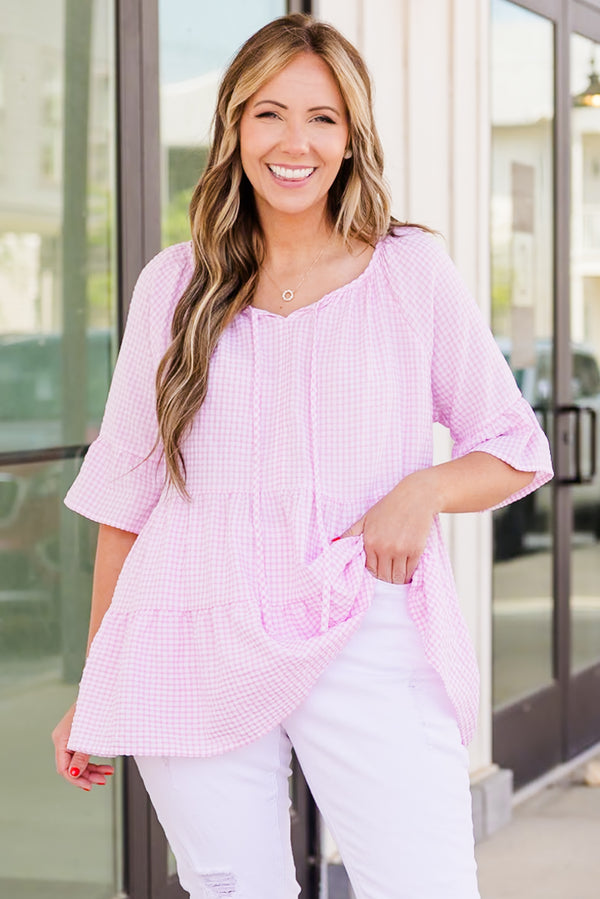 Plus Size pink and white gingham tiered top with elbow-length ruffle sleeves and a tie neckline.