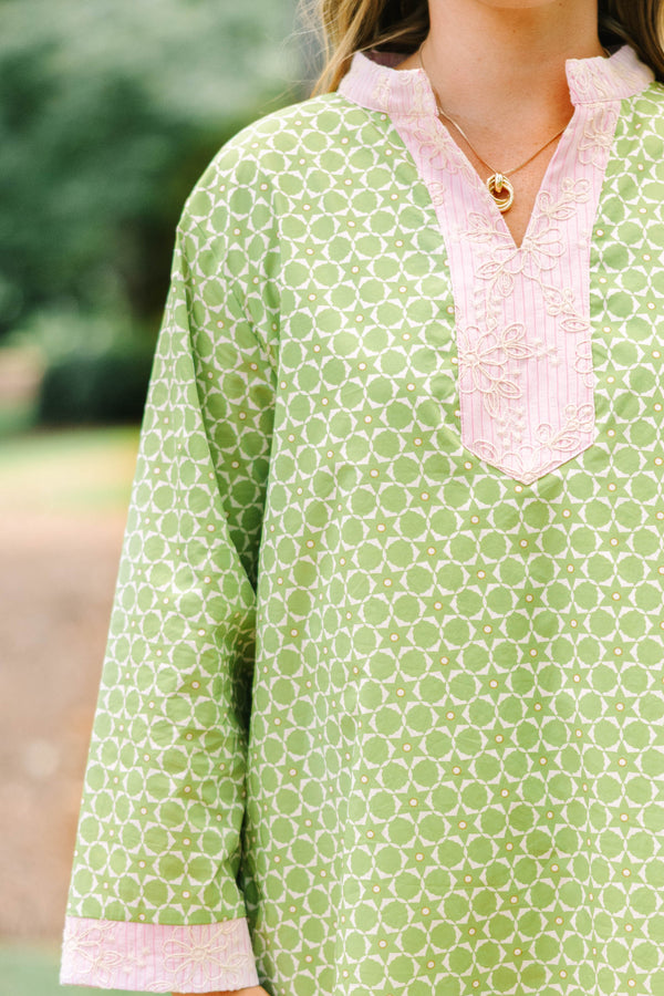 Plus size olive green geometric print tunic dress with pink embroidered trim and side pockets.
