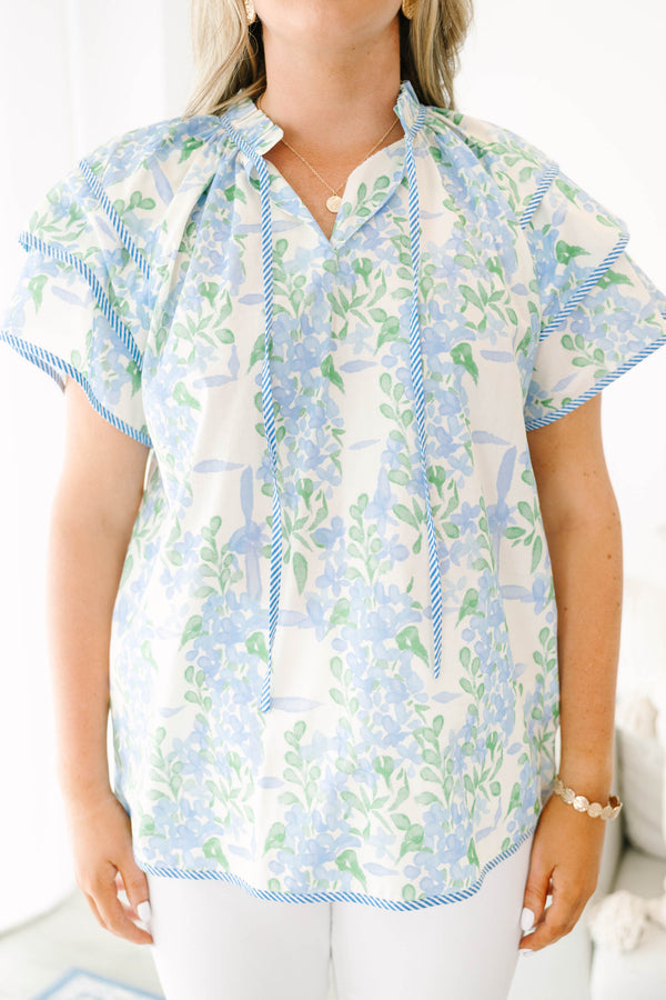Plus size blue floral ruffle sleeve top with v neckline that ties with tassels across the neck