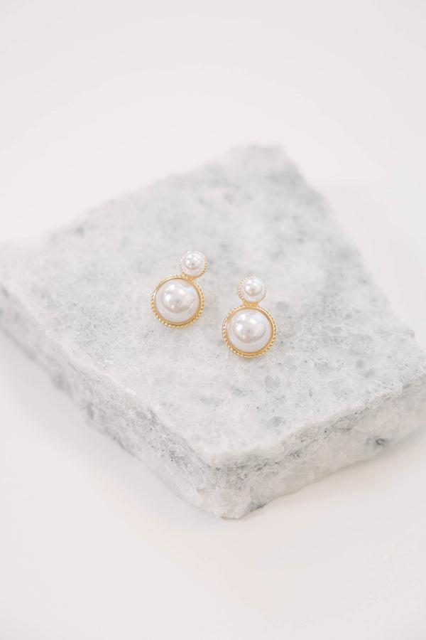 Pearl drop earrings with gold-toned settings.