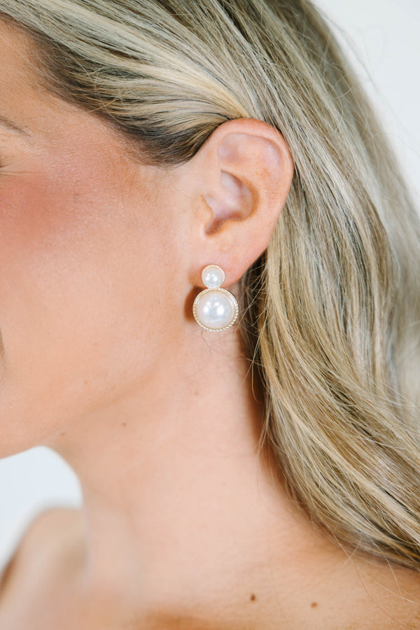 Pearl drop earrings with gold-toned settings.