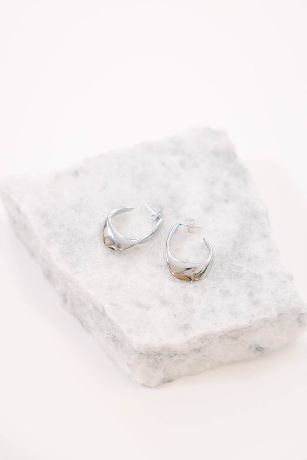 Silver earrings, featuring a modern twisted hoop design.