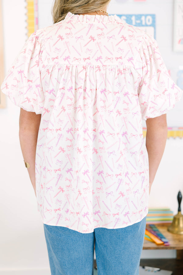 Plus Size pink and white blouse with pencil and bow print, ruffled v-neck, and bubble sleeves.