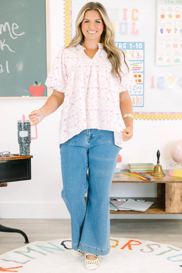 Plus Size pink and white blouse with pencil and bow print, ruffled v-neck, and bubble sleeves.