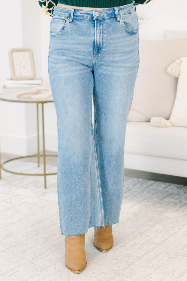 Plus Size medium wash wide-leg jeans with a high-rise fit and raw, frayed hems.