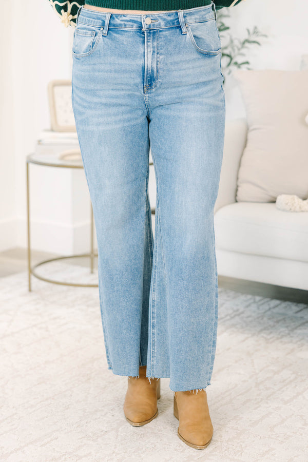 Plus Size medium wash wide-leg jeans with a high-rise fit and raw, frayed hems.
