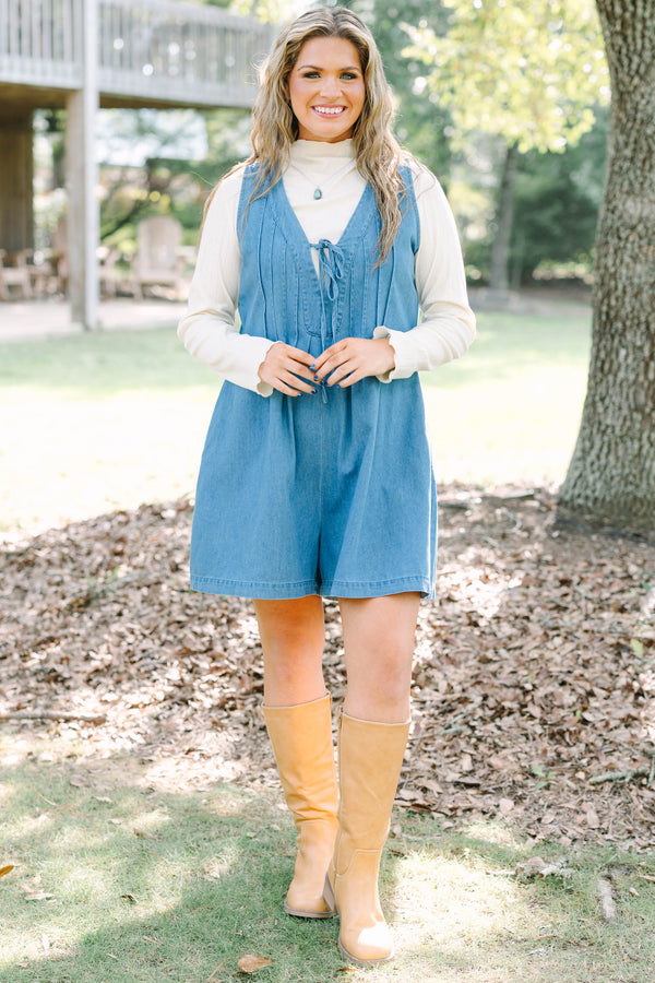 Plus Size denim romper with a tie-front V-neckline and pleated details over a white turtleneck.