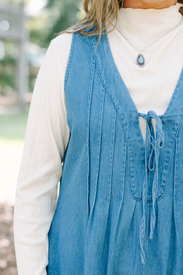 Plus Size denim romper with a tie-front V-neckline and pleated details over a white turtleneck.
