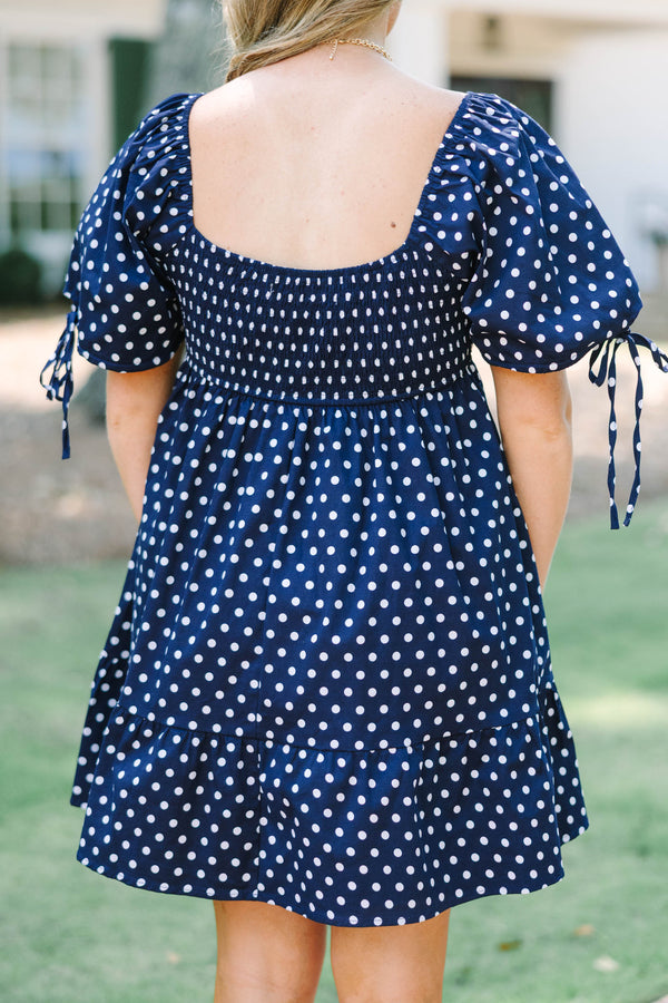 Plus Size navy blue polka dot cotton dress with puff sleeves, tie details, and a tiered skirt.