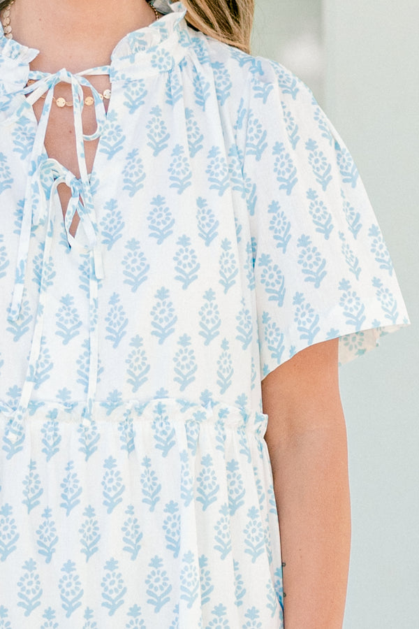 Plus Size white cotton dress with blue floral print, split neckline, neck ties, and tiered skirt.