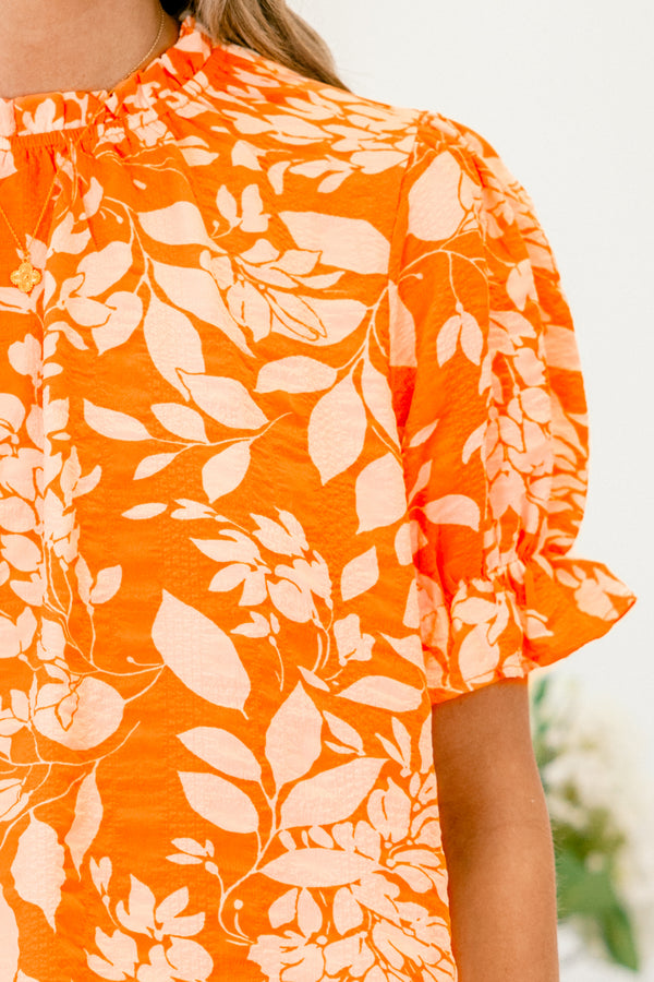 Chic Soul plus size clothing, orange top with a white floral pattern and bubble sleeves that have small ruffle detailing on the ends 