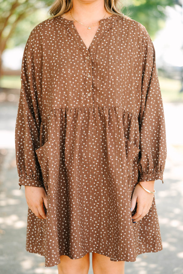 Plus Size brown long-sleeve mini dress with a white floral print, buttoned V-neck, and pockets.