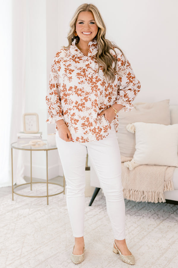 Chic Soul plus size clothing, ivory top with long sleeves that have a ruffle detail at the bottom of each sleeve as well a orange floral pattern and eyelet details throughout the top 