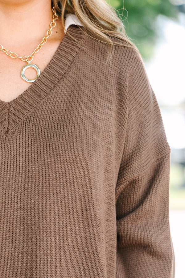 Plus size brown V-neck Sweater with a flowy fit and ribbed hem over blue jeans.