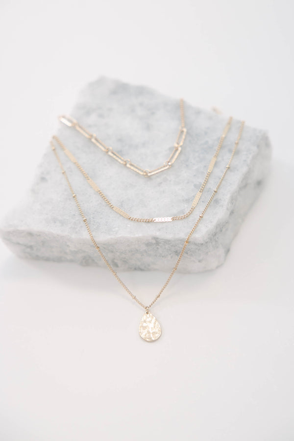 Gold layered necklace with a teardrop pendant.