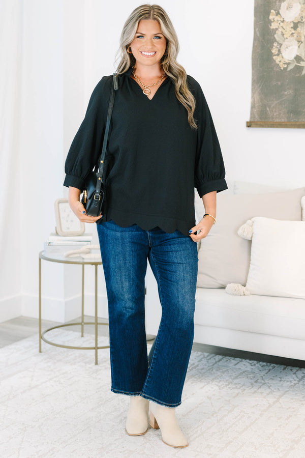 Plus size black top with a flowy fit, V-neckline, and textured polyester fabric.
