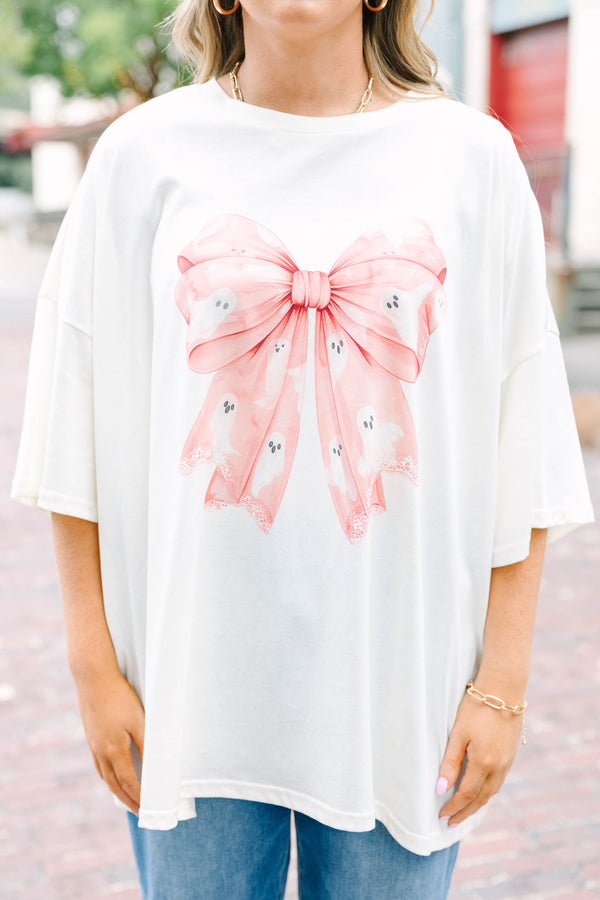 Woman wearing an ivory Girly Ghost Boyfriend Tee with a large pink bow and ghost print.