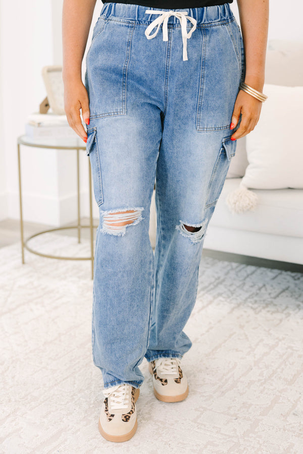 Plus Size light wash cargo jeans with a drawstring waist, distressed knees, and utility pockets.