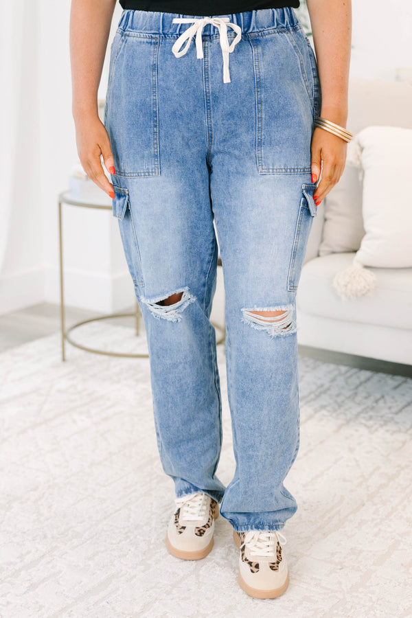 Plus Size light wash cargo jeans with a drawstring waist, distressed knees, and utility pockets.