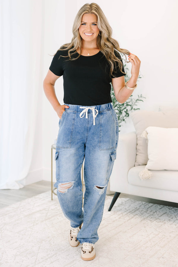 Plus Size light wash cargo jeans with a drawstring waist, distressed knees, and utility pockets.