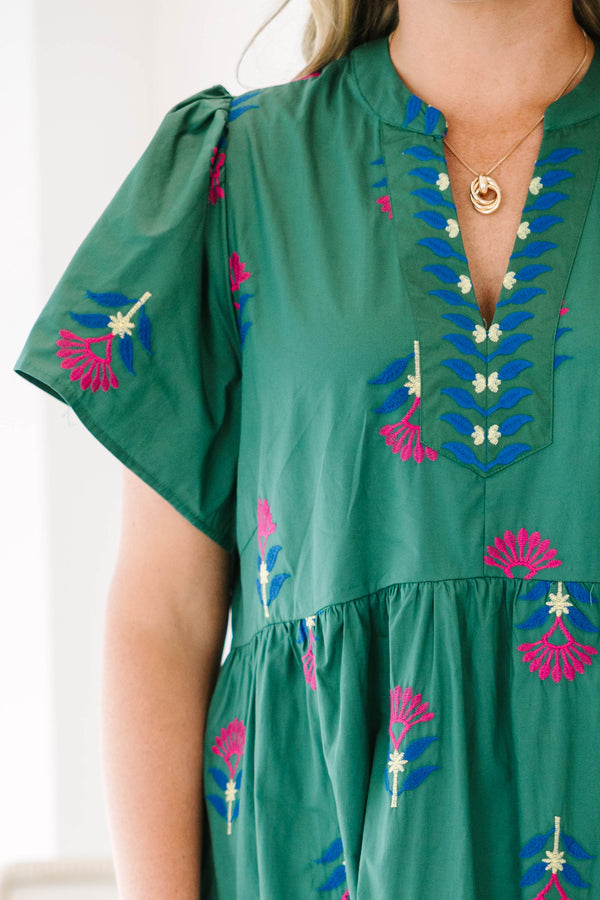 Plus size hunter green midi dress with pink floral embroidery, flowy fit, and tiered ruffle hem.