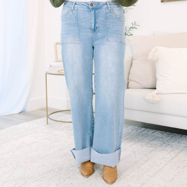 Plus size light wash high-rise wide-leg jeans featuring oversized cuffed hems and patch pockets.