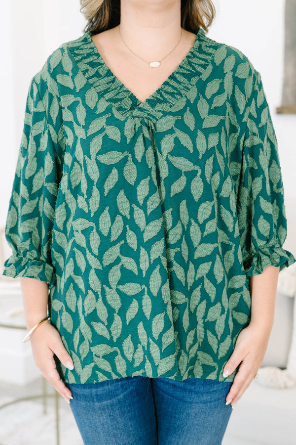 Plus size woman in a green leaf print top with a flowy fit, V-neckline, and ruffled sleeves.