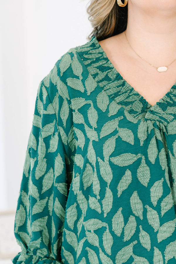 Plus size woman in a green leaf print top with a flowy fit, V-neckline, and ruffled sleeves.