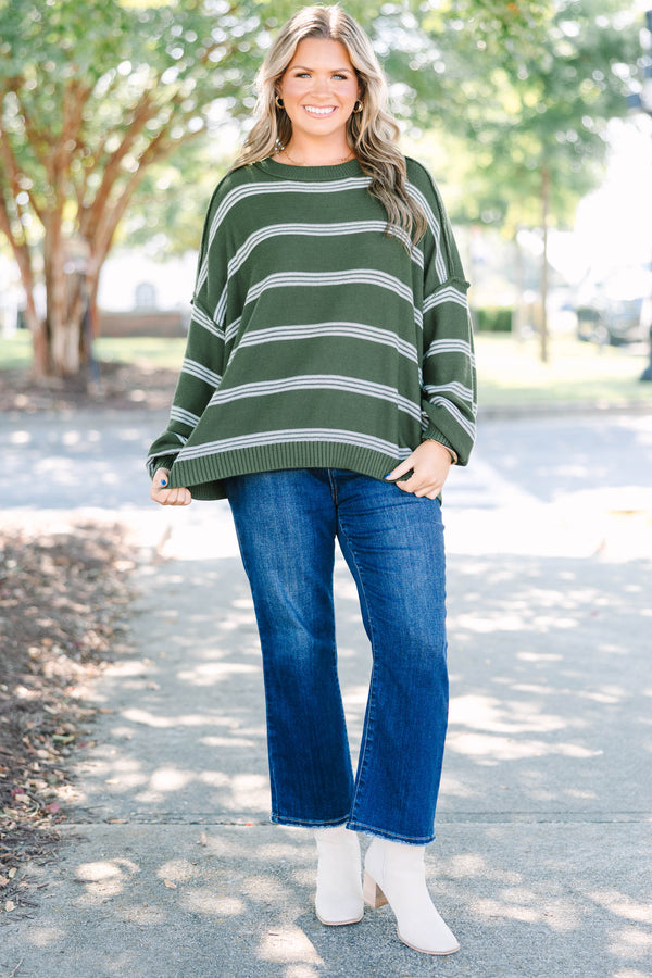 Plus size woman in an olive green oversized striped sweater with a relaxed, flowy fit.