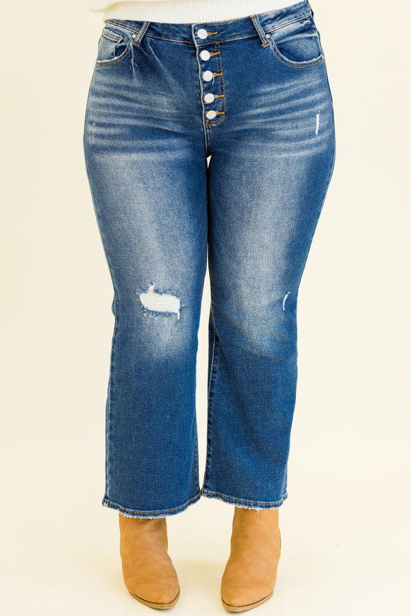 mid-waisted subtle flare cropped dark wash denim jeans with slight distressed detailing along knees and multiple silver buttons on waistline 
