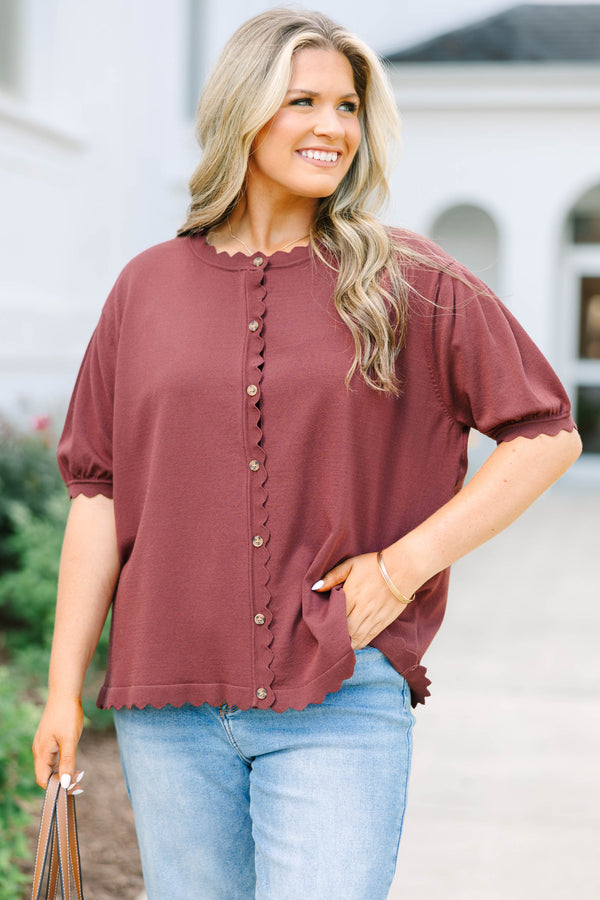 Plus size woman in a brown short sleeve cardigan with scalloped edges and a button-down front.
