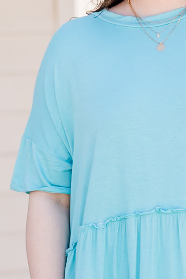 Plus Size seafoam short-sleeve top with a ruffle hem and crew neckline paired with white pants.
