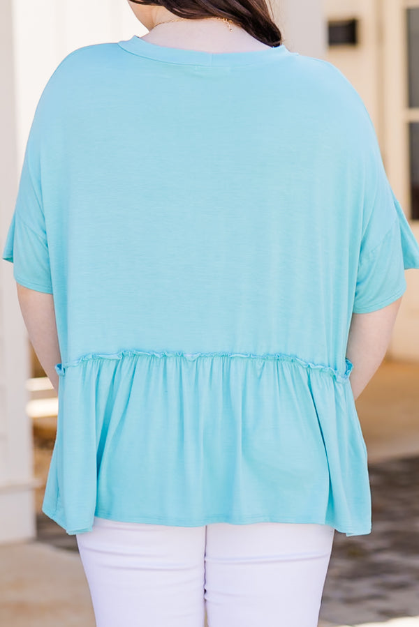 Plus Size seafoam short-sleeve top with a ruffle hem and crew neckline paired with white pants.