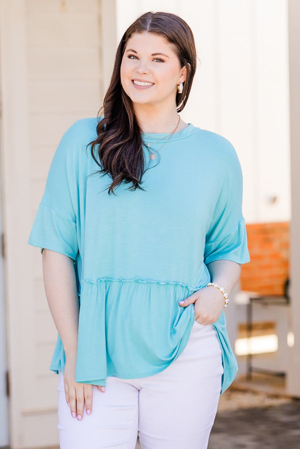 Plus Size seafoam short-sleeve top with a ruffle hem and crew neckline paired with white pants.