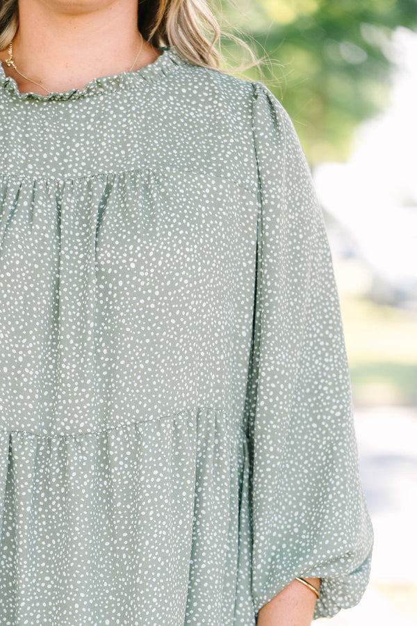 Plus size olive green tiered mini dress with white polka dots and a flowy, relaxed fit.