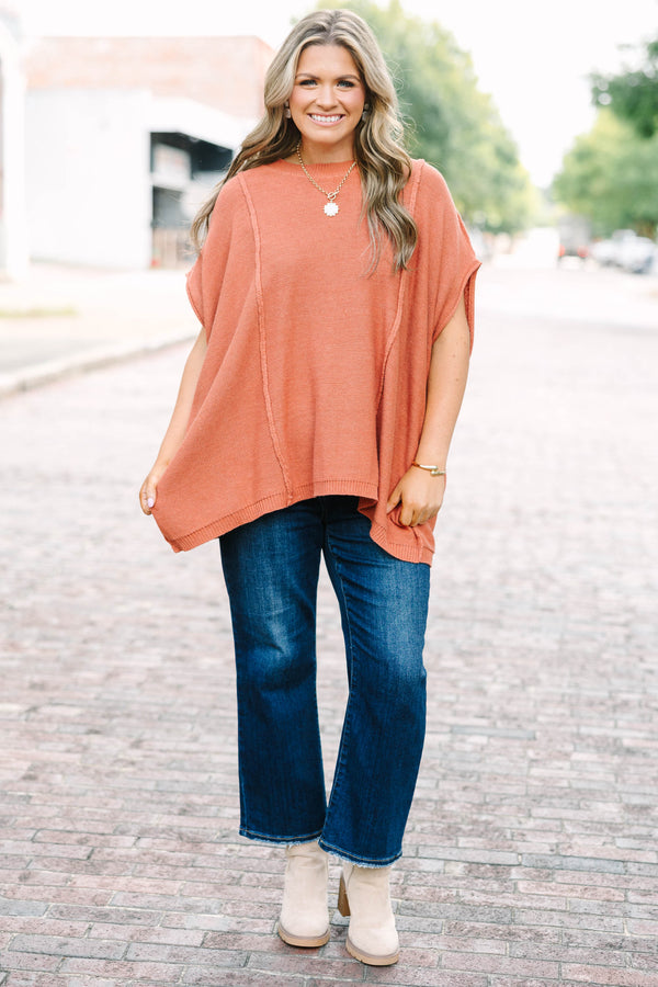 Plus size rust-colored, flowy knit sweater with a relaxed fit and short poncho sleeves.