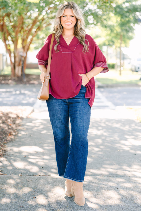 Plus size burgundy top with a flowy fit, V-neck, and striped sleeve details.