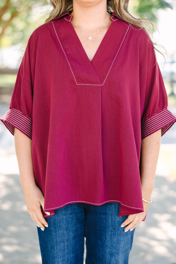 Plus size burgundy top with a flowy fit, V-neck, and striped sleeve details.