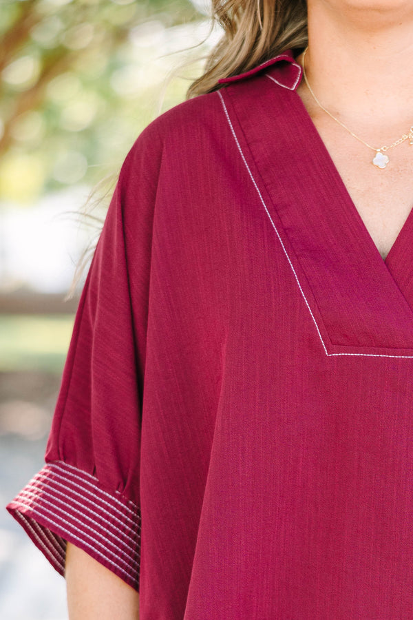 Plus size burgundy top with a flowy fit, V-neck, and striped sleeve details.