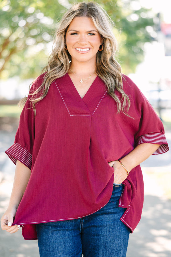 Plus size burgundy top with a flowy fit, V-neck, and striped sleeve details.