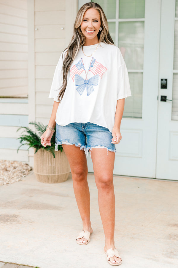 Plus Size white vintage wash tee with an American flag and blue bow graphic and unfinished hems.