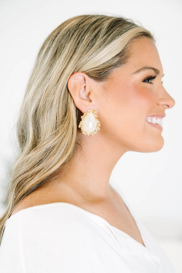 Gold statement earrings with a teardrop white stone and rippled gold border.