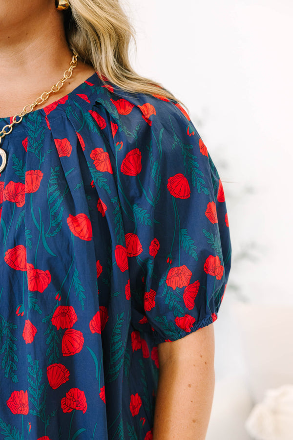 Plus size navy top with red poppy print, flowy fit, and puff sleeves.