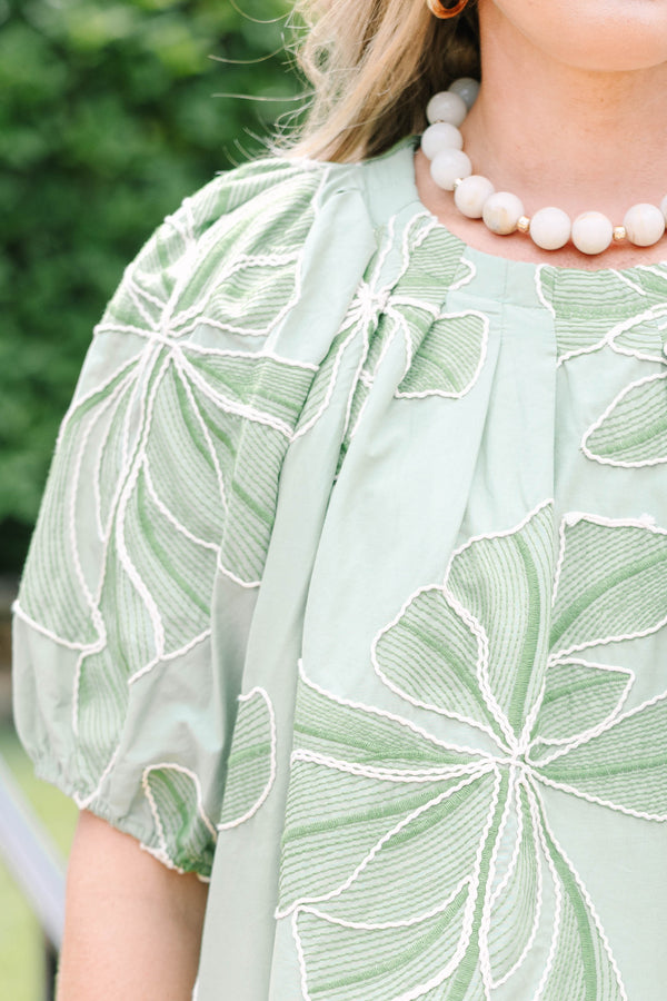 Plus Size olive top with white floral embroidery, elastic puff sleeves, and a round neckline.