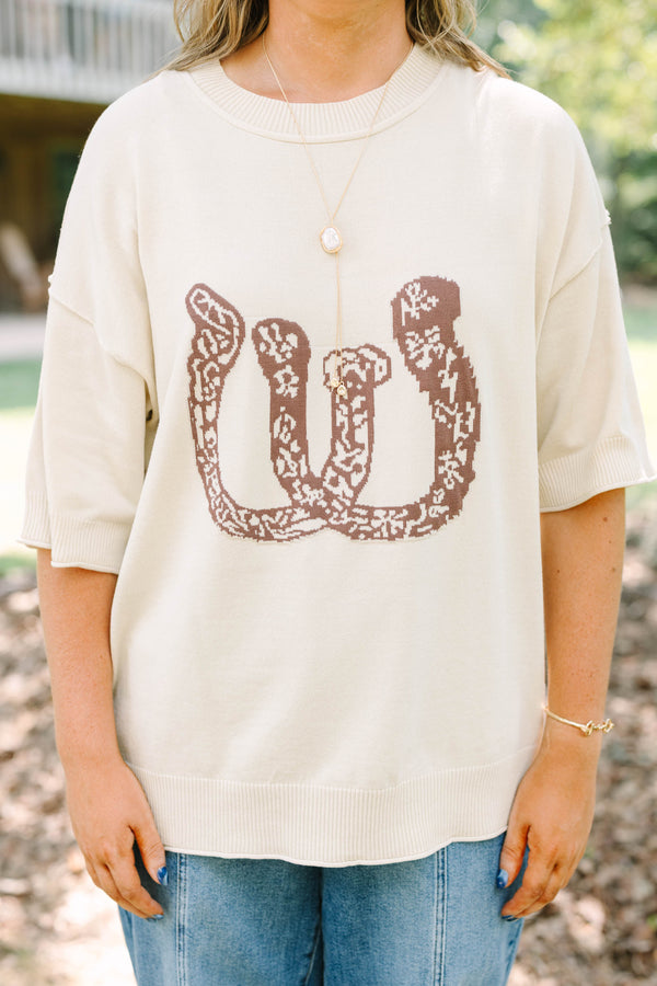Plus Size cream short sleeve sweater with a brown horseshoe graphic and blue denim jeans.