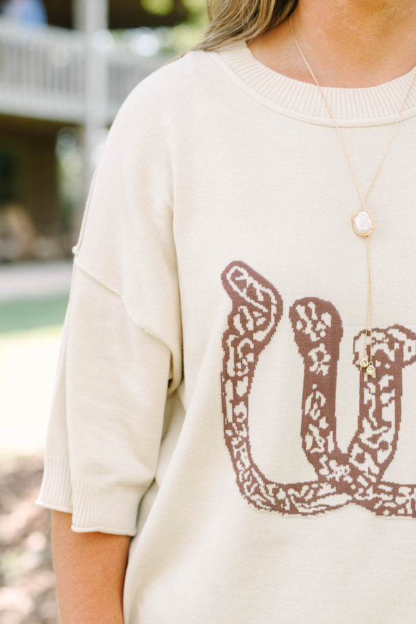 Plus Size cream short sleeve sweater with a brown horseshoe graphic and blue denim jeans.