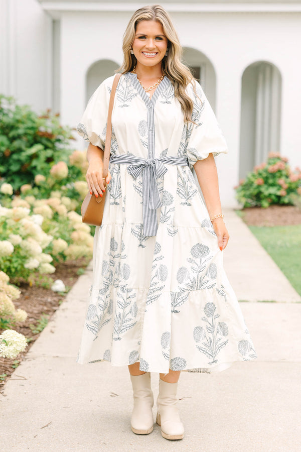Plus size cream tiered midi dress with navy blue floral print, blue striped sash, and puff sleeves.