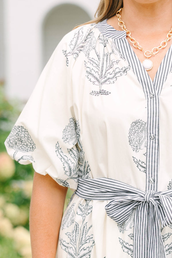Plus size cream tiered midi dress with navy blue floral print, blue striped sash, and puff sleeves.