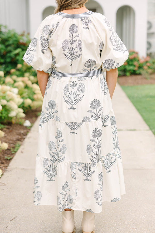 Plus size cream tiered midi dress with navy blue floral print, blue striped sash, and puff sleeves.