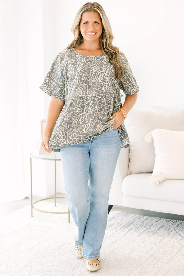 Plus size woman in a light leopard print peplum top with a flowy fit and short sleeves.